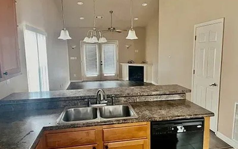 Kitchen sink and dark granite countertop overlooking living room