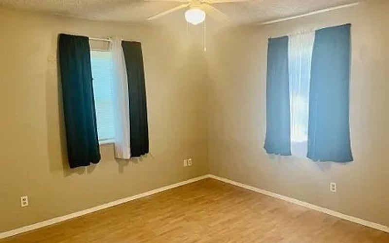 Bedroom with blue curtains and ceiling fan