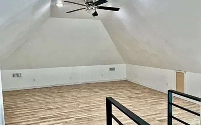 Upstairs loft with ceiling fan and black railing