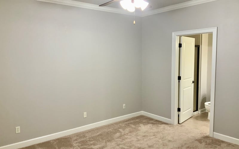 Bedroom with ceiling fan, crown molding, and ensuite bathroom door