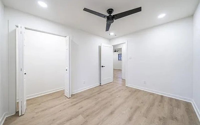 Bedroom with ceiling fan, closet, and hallway view