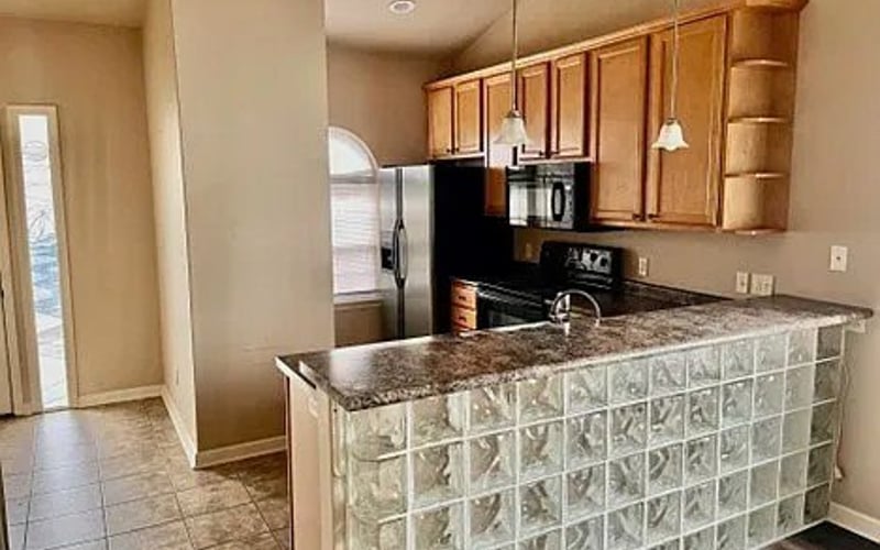 Kitchen with wood cabinets, granite island, and glass block bar