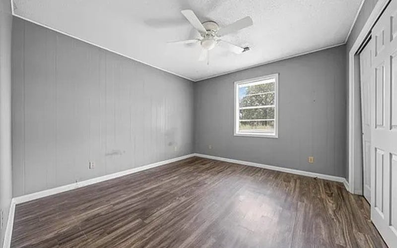 Bedroom with grey walls, ceiling fan and hardwood floors