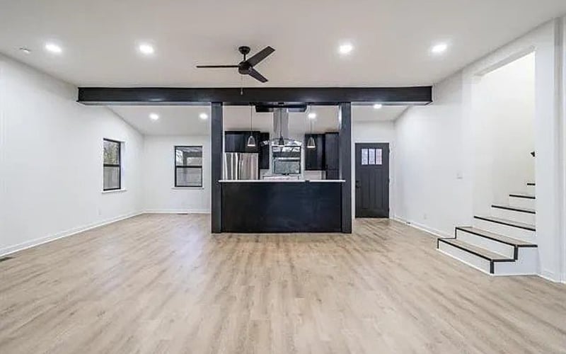 Open living area with kitchen island and staircase