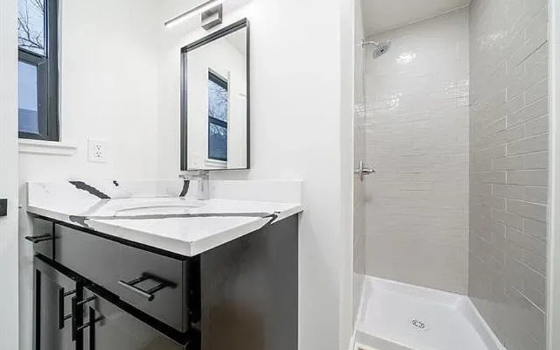 Bathroom with dark vanity and tile shower
