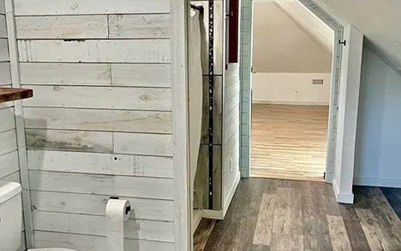 Upstairs bathroom with shiplap walls and wood floors