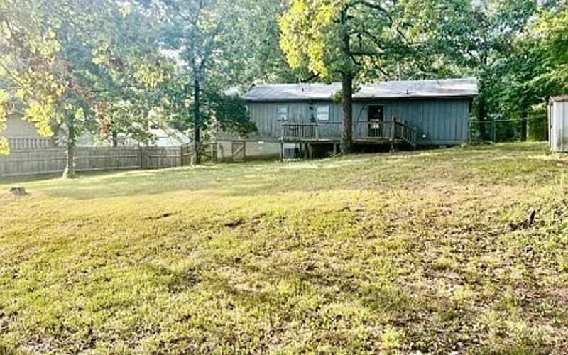 Rear yard with open lawn and wooded backdrop