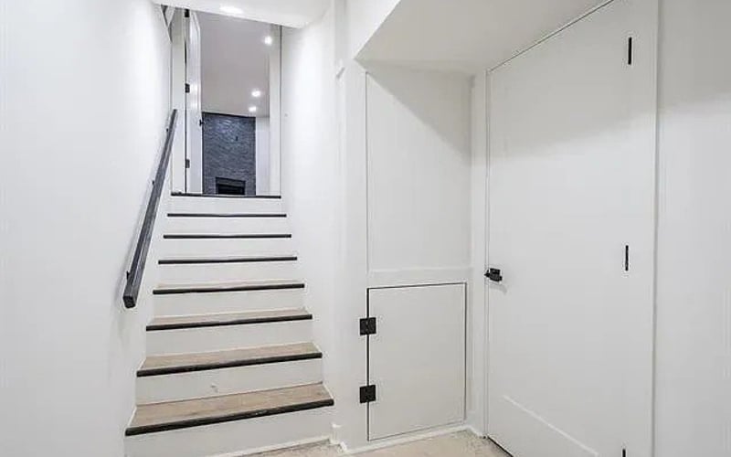 Staircase with black railing and storage door