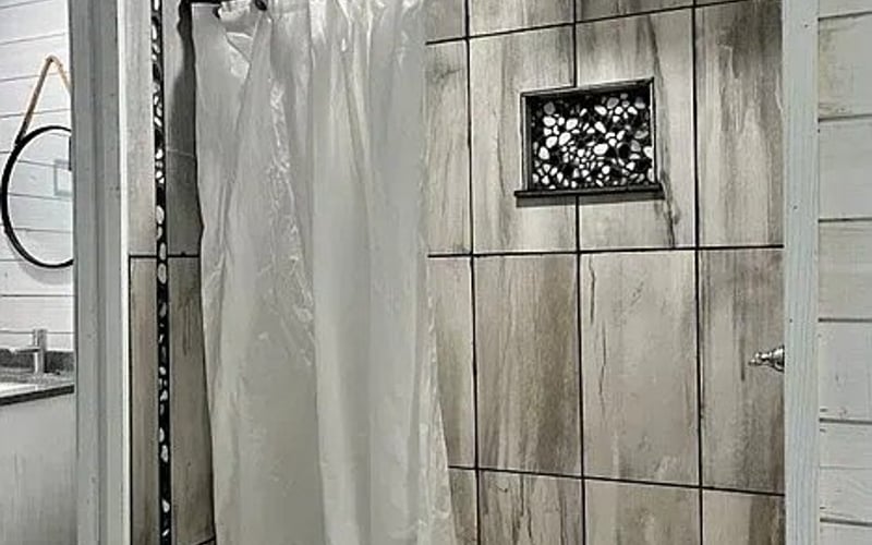 Tiled shower with rain head and mosaic niche