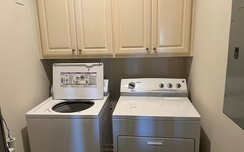 Laundry room with washer, dryer, and overhead cabinets